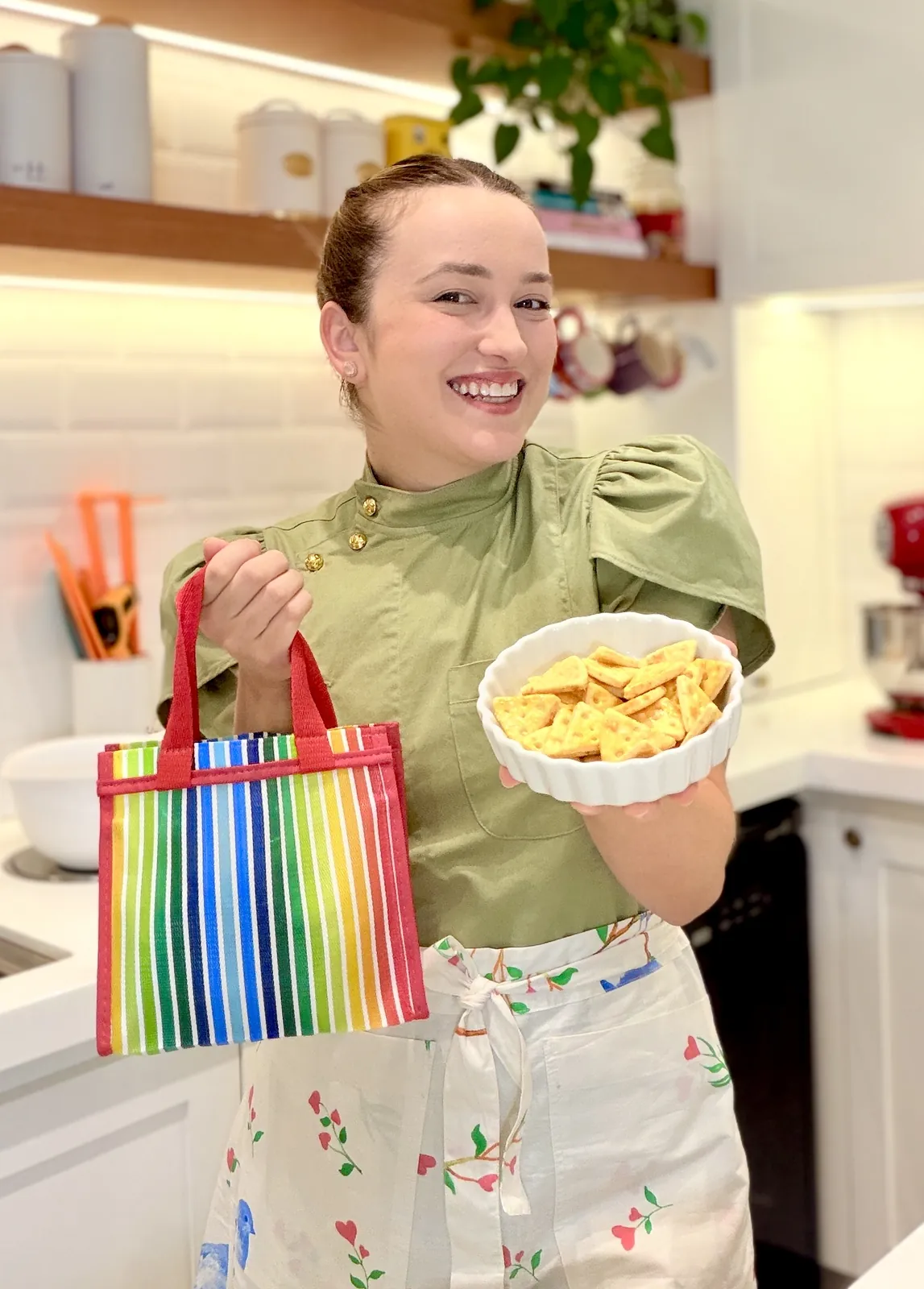 Mari Molina segurando uma sacola listrada e uma travessa de sequilhos