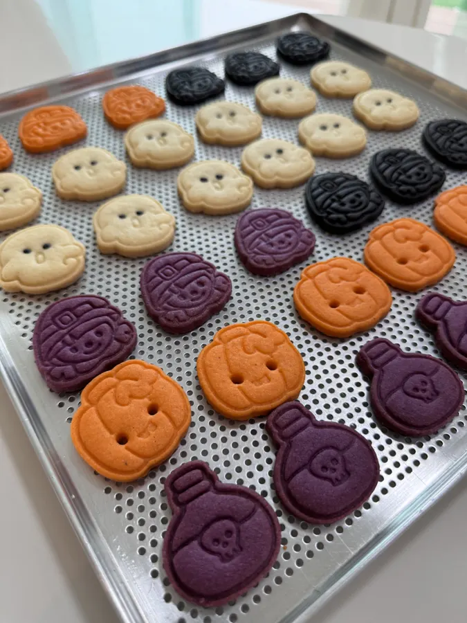 Biscoitos coloridos em roxo, laranja e chocolate na assadeira